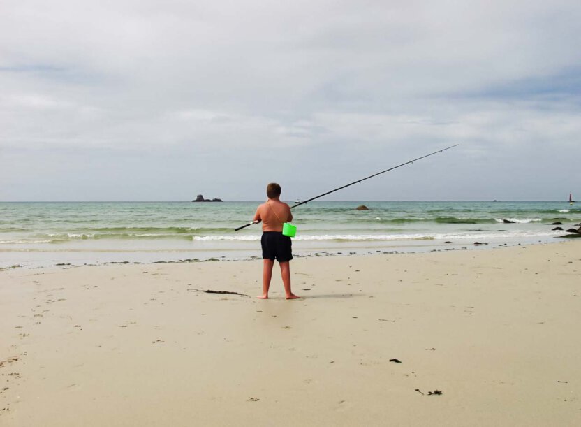 Kind mit Angel am Strand in der Bretagne