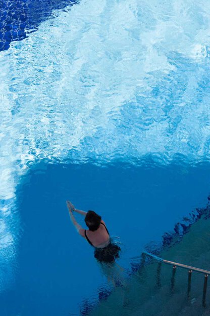 Frau schwimmt am Pool